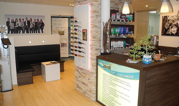 Modernes Optiker-Geschäft mit Beratungstheke, Brillenauswahl und Sitzbereich.