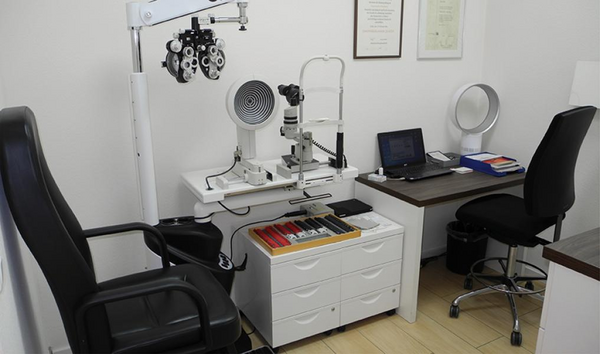 Moderne Augenarztpraxis mit Untersuchungsgeräten, Sehtest-Station und Schreibtisch.